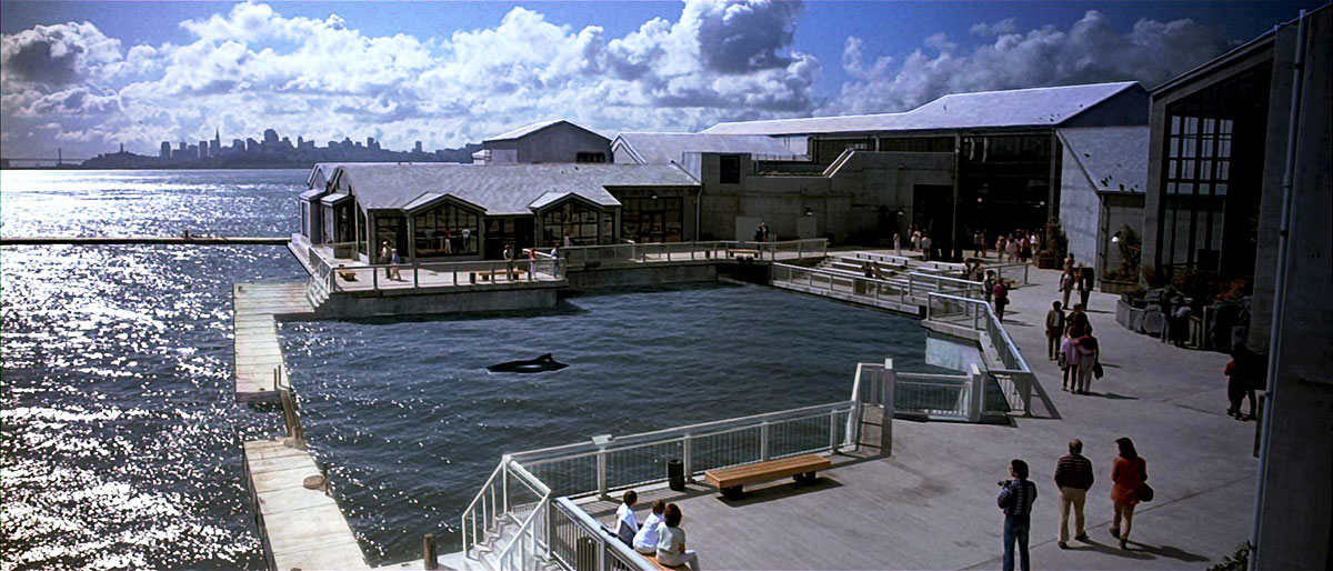 A screenshot from "Star Trek IV: The Voyage Home" showing the back of the Cetacean Institute, where they keep their whales. The northern portion of San Francisco can be seen in the background, with the Bay Bridge to the left.